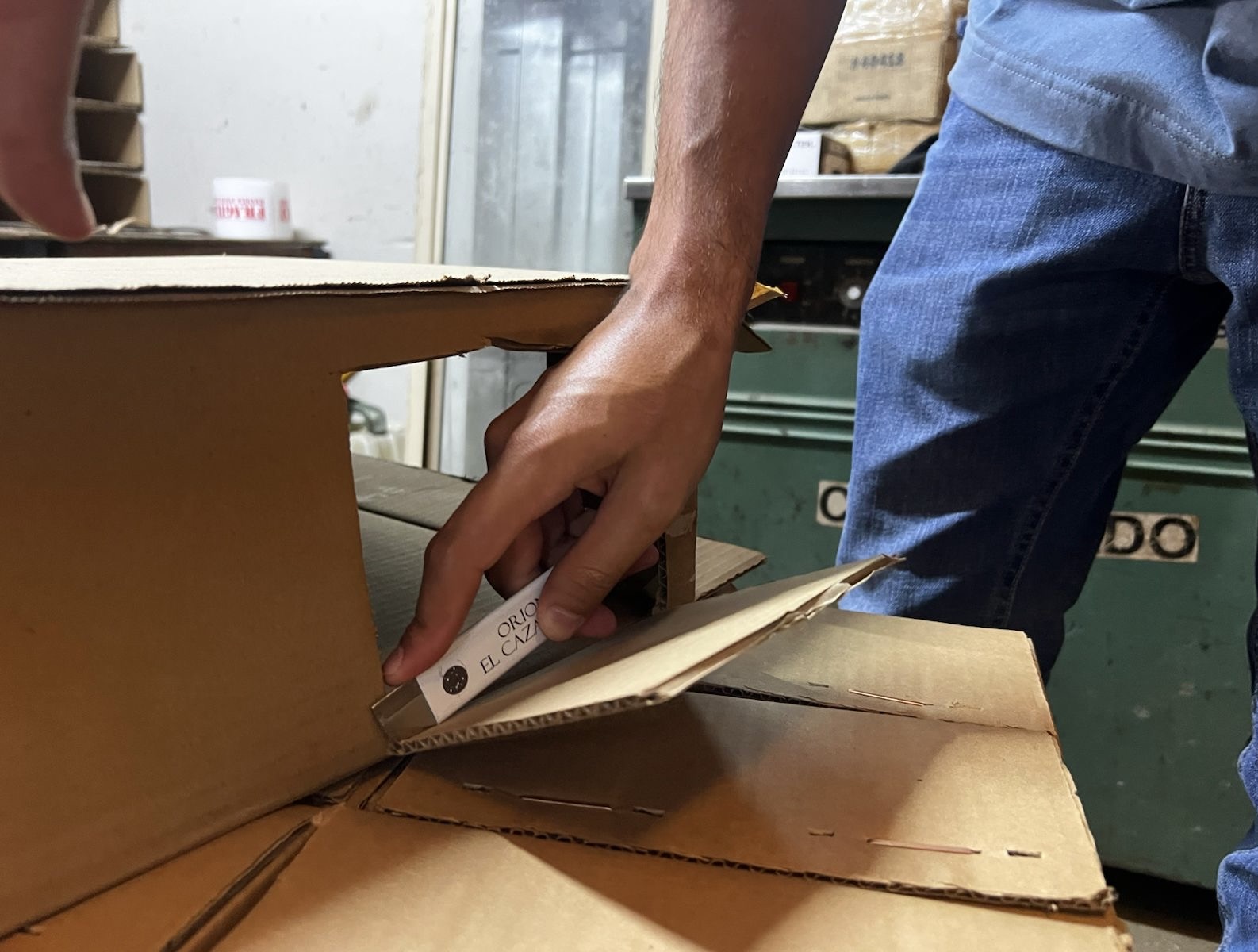 Mano usando el Cortador de Cajas STARMATIC para abrir una caja de cartón